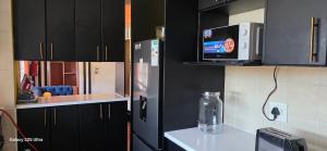 una cucina con armadi neri e frigorifero di VB Accomodation (STATION HOME) a Città del Capo