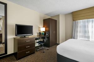 ein Hotelzimmer mit einem Bett und einem Schreibtisch mit einem Fernseher in der Unterkunft Sleep Inn Fayetteville North in Fayetteville