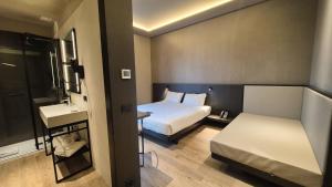 a small hotel room with a bed and a sink at Kira Suites Hotel Milano in Milan +5 photos
