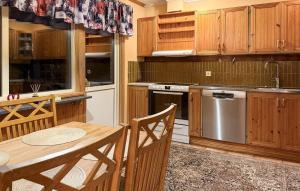 een keuken met houten kasten, een tafel en een wastafel bij 4 Bedroom Pet Friendly Home In Karlstad in Våxnäs