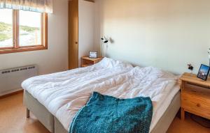 ein Schlafzimmer mit einem weißen Bett und einer blauen Decke darauf in der Unterkunft Amazing Home In Myggenäs With Sauna in Höviksnäs
