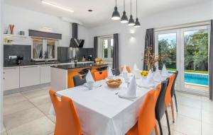 eine Küche und ein Esszimmer mit einem weißen Tisch und orangefarbenen Stühlen in der Unterkunft Stunning Home In Brecevici in Brečevići