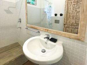 ein Badezimmer mit einem weißen Waschbecken und einem Spiegel in der Unterkunft Pine Cone Cottages, Ella in Ella