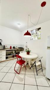 eine Küche mit einem weißen Tisch und roten Stühlen in der Unterkunft Casa a 100mts da praia in Ilhabela