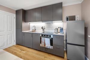 a kitchen with gray cabinets and a refrigerator at Lovely Ealing 3 Bed Flat in Ealing