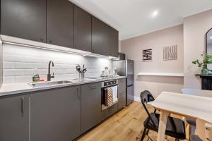 a kitchen with stainless steel appliances and a table at Lovely Ealing 3 Bed Flat in Ealing