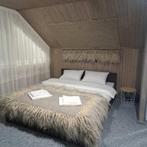 a bedroom with a large bed with two towels on it at GORY & TYSHA Гори і Тиша in Yavoriv