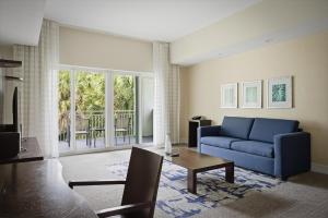 ein Wohnzimmer mit einem blauen Sofa und einem Tisch in der Unterkunft Spacious 1BR Loft Villa - Pool Golf - Doral Downtown in Miami