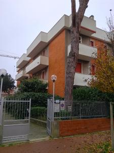 een hek voor een gebouw met een boom bij Il sorriso romagnolo in Misano Adriatico