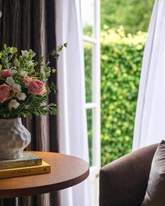 a vase of flowers on a table next to a window at Buxted Park Hotel in Uckfield