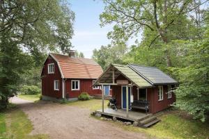 a small red house with a porch in the woods at HAL657-Knaered-Bjoerkered-72 in Körsveka