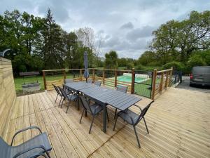 une terrasse en bois avec une table et des chaises ainsi qu'une piscine dans l'établissement La maison Callinora, à La Chapelle-Saint-Étienne