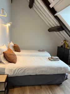 two beds in a room with white walls and wooden floors at Le Laurencin Sens - Le Comble - Cœur de ville in Sens
