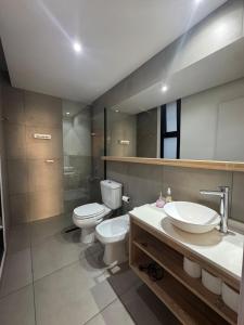 a bathroom with a toilet and a sink and mirror at Canela Loft Rosario in Rosario