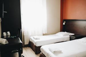 LimasにあるLogis Hôtel Nova - Villefranche sur Saôneのベッド2台と机があるホテルの部屋