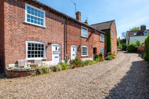 a brick house with two benches on a gravel driveway at 2 Bed in Beccles oc-puddin in Beccles