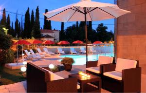 een terras met stoelen en een parasol en een zwembad bij Cozy Apartment In Cilipi in Čilipi +6 foto's