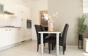 een keuken met een tafel, zwarte stoelen en een vaas met bloemen bij Cozy Apartment In Cilipi in Čilipi