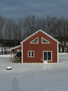a red house in the middle of a snow covered field at Barn Cottage close to Smugglers Notch in Cambridge