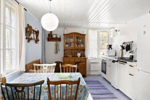 eine Küche mit einem Tisch und Stühlen sowie eine Küche mit weißen Geräten in der Unterkunft OGO631 Boxholm - Stjärnesand Sågstugan 1 in Ormsjötorp