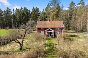 ein rotes Haus mitten auf einem Feld in der Unterkunft OGO631 Boxholm - Stjärnesand Sågstugan 1 in Ormsjötorp + 20 Fotos