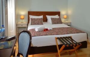 a bedroom with a large bed with a desk and a chair at Dukes Corner Guest House in Porto