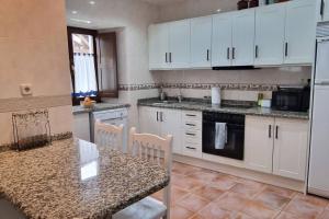 Una cocina con gabinetes blancos y una mesa con sillas. en La Ayalga casa de campo, en Ardisana