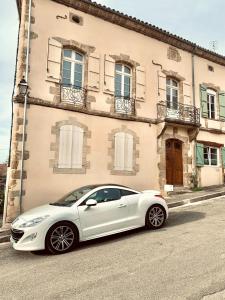 ein weißes Auto, das vor einem Gebäude geparkt ist in der Unterkunft Eucalyptus - Élégance près du circuit de Nogaro in Manciet