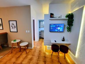 ein Wohnzimmer mit Stühlen und einem TV an der Wand in der Unterkunft Apartamento Centro de Capão da Canoa in Capão da Canoa