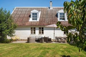 uma casa branca com uma mesa e cadeiras e um guarda-sol em SKA694-Hoeganaes-Hustoftavaegen-95 em Höganäs