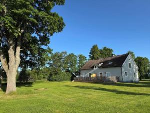 a large white house in a field with a tree at OGO781-Mjoelby-Norrby-Naesloesegard-1 in Mjölby