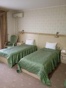 ein Hotelzimmer mit zwei Betten und einem Stuhl in der Unterkunft Hotel Majestic City Center in Iaşi