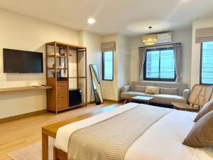 ein Schlafzimmer mit einem Bett, einem Fernseher und einer Couch in der Unterkunft Little Stay Bophut - Samui in Ko Samui