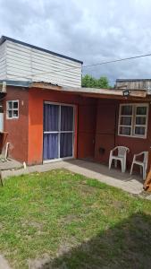 ein rotes Haus mit Terrasse und einem weißen Stuhl in der Unterkunft El Rinconcito in El Bolsón