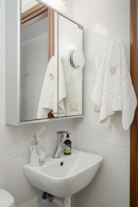 ein weißes Badezimmer mit Waschbecken und Spiegel in der Unterkunft Family Home, with Sea & Mountain view in Kalamaki + 22 Fotos