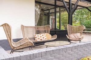 3 sillas de mimbre y una mesa en un porche en Vakantiepark De Kremmer, en Gasselte