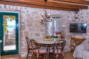een eetkamer met een tafel, stoelen en een tv bij House Vedrana in Igrane