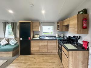 een keuken met houten kasten en een zwarte koelkast bij D & A Southview Getaway in Toynton All Saints