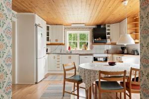 uma cozinha com mesa e cadeiras e uma cozinha com electrodomésticos brancos em KRO084-Linneryd-Skogsholm-Skogsryd em Sandvik
