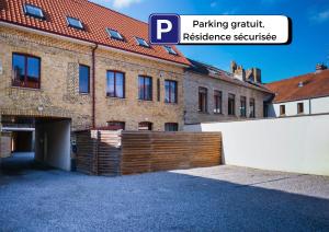 een bakstenen gebouw met een houten hek ervoor bij Appartement Centre Saint-Omer, Parking privé gratuit in Saint-Omer
