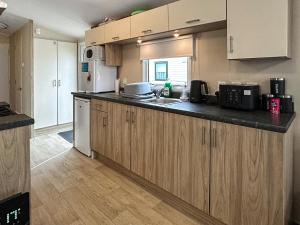 een keuken met houten kasten en een aanrechtblad bij Ali B's Craig Tara in Ayr