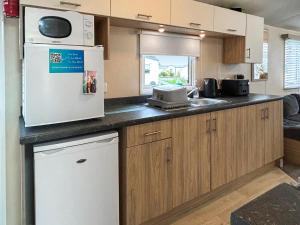 een keuken met een koelkast en een magnetron bij Ali B's Craig Tara in Ayr