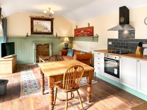 eine Küche und ein Wohnzimmer mit einem Holztisch und Stühlen in der Unterkunft Barnside Cottage - Uk50574 in Hayton