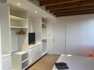 a white room with a bed and a television at Villa fleurs d'Antalia in Anse-Bertrand
