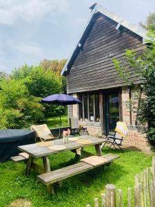 Maison au bord de riviere , proche de la mer- spa semi rigide plein air en option في Bacqueville-en-Caux: طاولة نزهة مع مظلة أمام المنزل