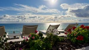 Una vista del océano con sillas y flores. en Perla Marina, en Nerja