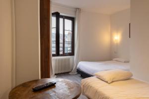 ein Zimmer mit zwei Betten und einem Tisch mit Fernbedienung in der Unterkunft Hôtel Du Bellay in Blois