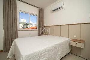 ein Schlafzimmer mit einem weißen Bett und einem Fenster in der Unterkunft Cobertura 07 Antares Bombinhas in Bombinhas