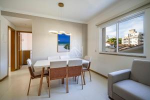 ein Esszimmer mit Tisch und Stühlen und einem Fenster in der Unterkunft Cobertura 07 Antares Bombinhas in Bombinhas