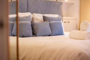 a bedroom with a bed with blue and white pillows at Little Net House - Pittenweem in Pittenweem